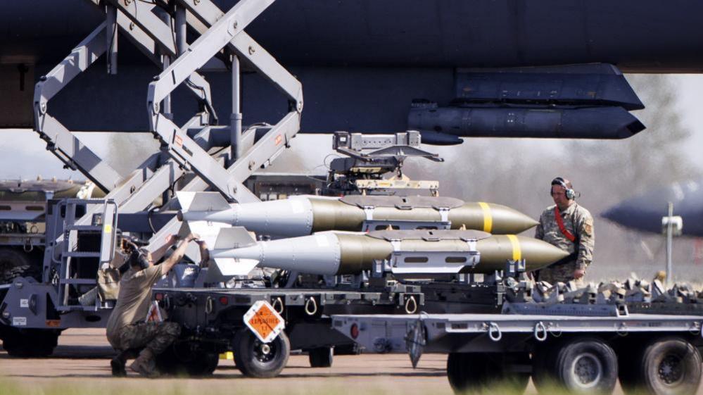 A member of the US military watches on as weapons are loaded onto an American aircraft at RAF Fairford