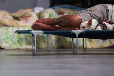 A man rests with his dog in a community hall on a camp bed in Le Porge.